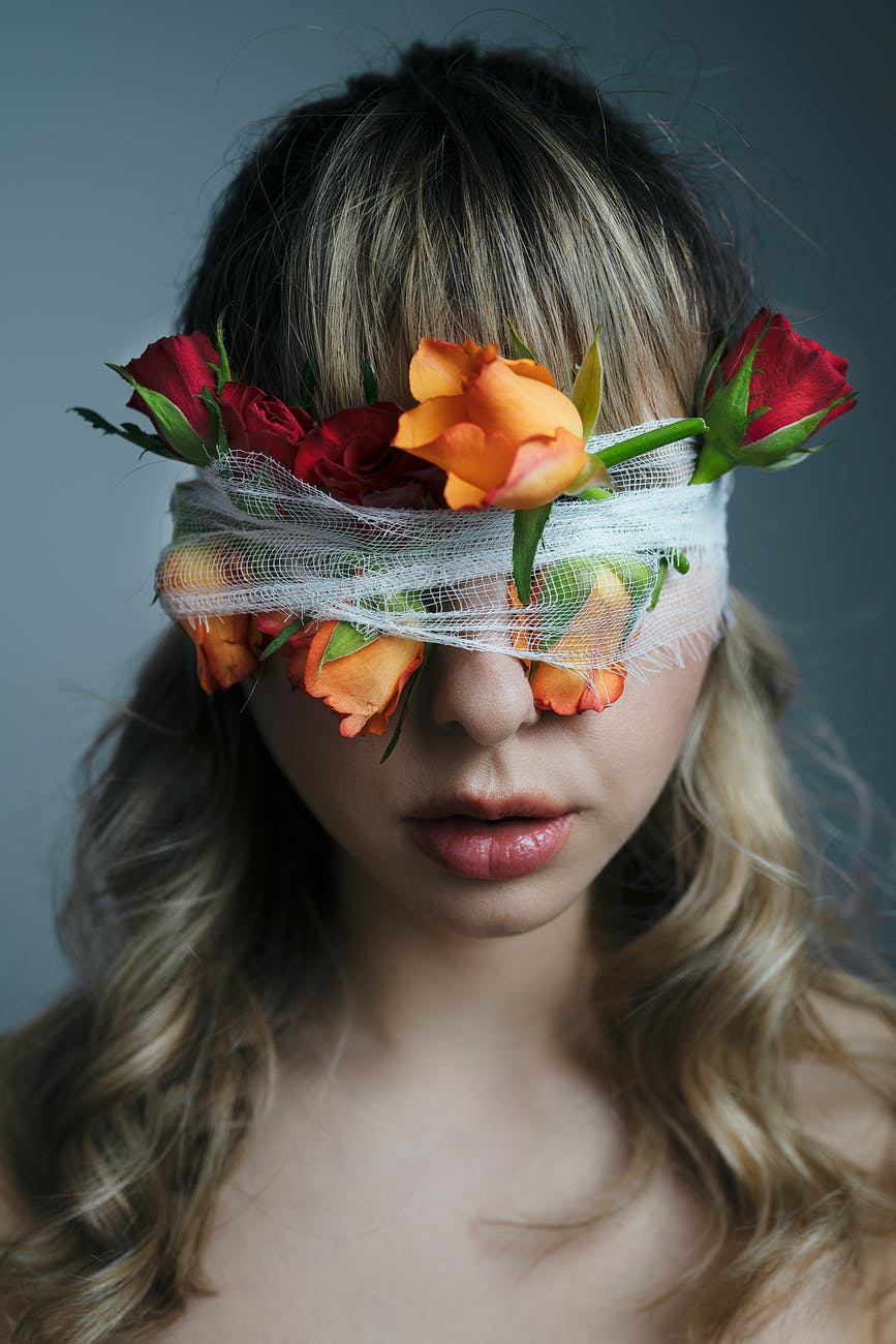 unrecognizable woman with blindfold and blooming roses